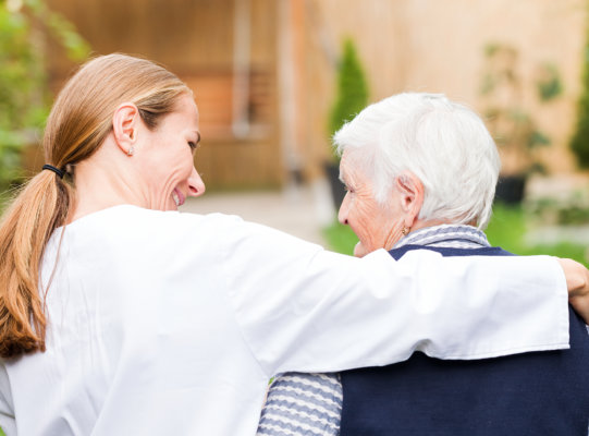 female carer and senior woman walking together